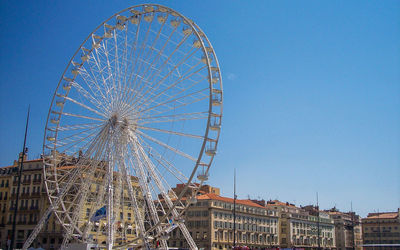 Low angle view of ferris wheel against blue sky