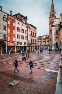 People on street against buildings in city