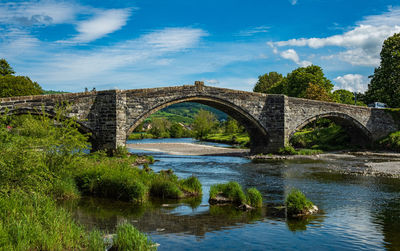 Arch bridge over river against sky