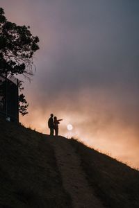 Low angle view of people standing on hill against sky