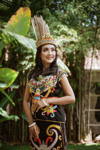 Portrait of young woman standing against plants