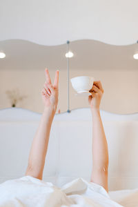 Young woman with a coffee mug in bed with white linens. minimal happy morning