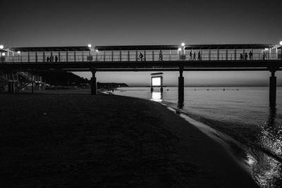 Bridge over sea against clear sky at night