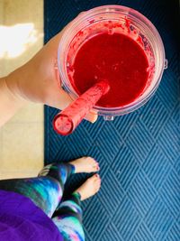 Low section of woman holding drink while standing on carpet