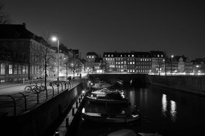 Illuminated bridge over river against sky in city at night