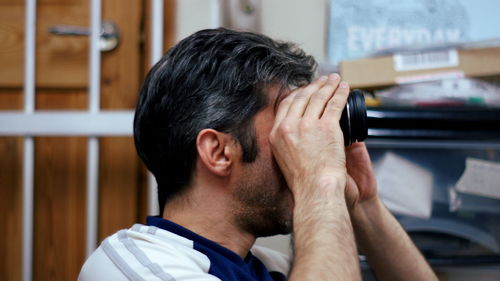 Close-up of man looking through camera lens