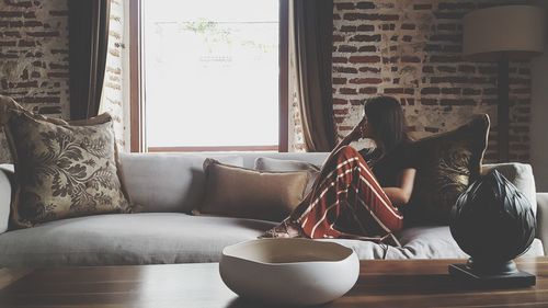 Thoughtful woman sitting on sofa at home