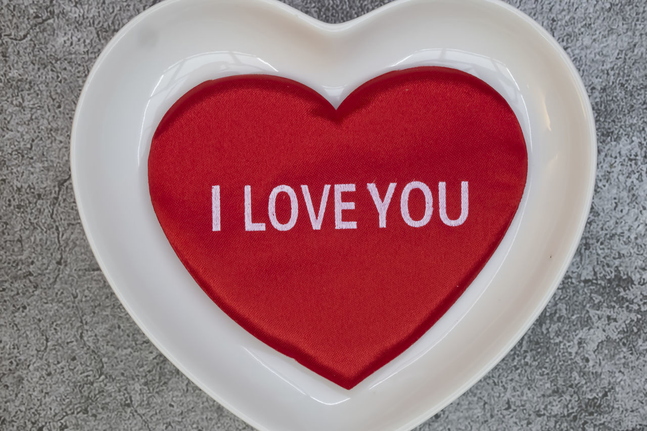 CLOSE-UP OF TEXT ON RED HEART SHAPE ON WHITE SURFACE