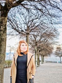 Portrait of woman standing by tree