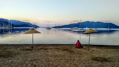 Rear view of man on beach against sky during sunset