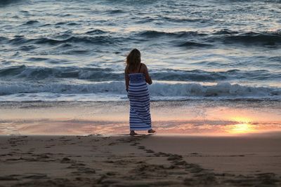 Rear view of woman standing on beach