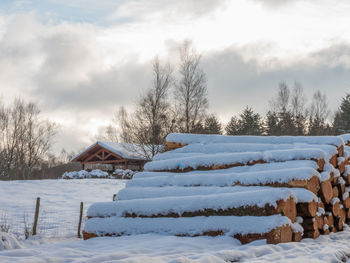 Snow covered field by building against sky