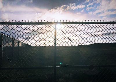 Fence on field against sky during sunset