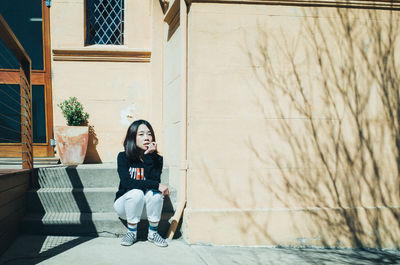 Full length portrait of woman sitting outdoors