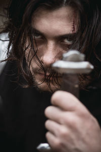 Close-up portrait of young man holding sword