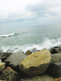 View of calm beach against cloudy sky