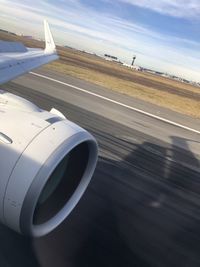 Airplane flying over airport runway against sky