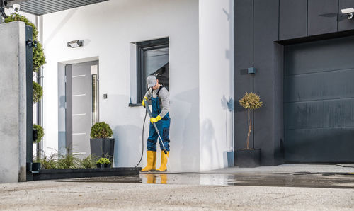 Manual worker cleaning floor outside home