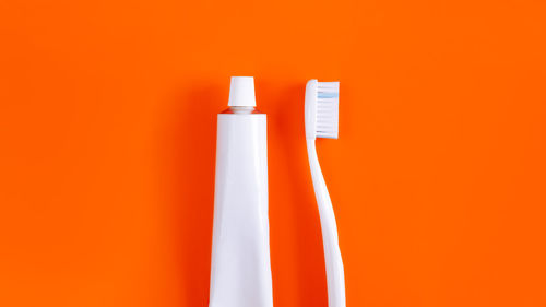 Close-up of toothbrush with toothpaste over orange background