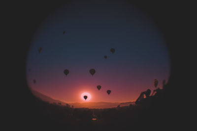 Silhouette hot air balloons against sky during sunset