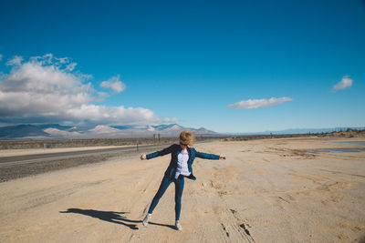 Boy standing on desert against sky