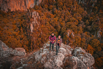 Portrait of friends standing on rock formation against trees
