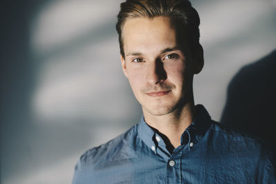 Portrait of confident businessman against wall in office