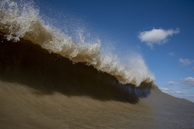 Waves splashing in sea against sky
