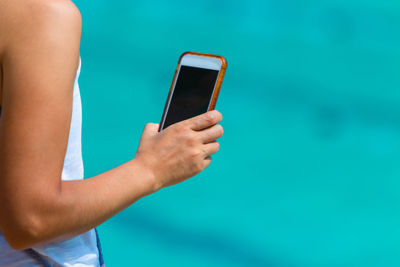 Midsection of man using mobile phone in swimming pool