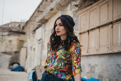 Young woman looking down while standing against brick wall