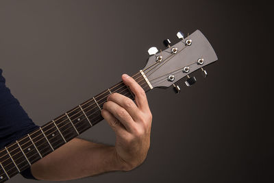 Cropped image of musician playing guitar against gray background