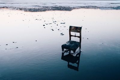 High angle view of weathered chair in sea