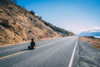 Man riding motorcycle on road against sky