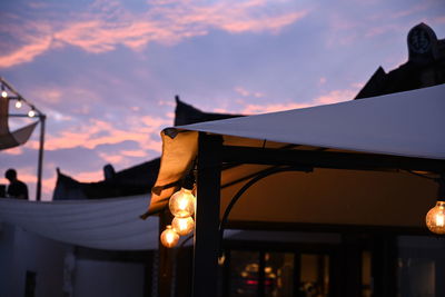 Low angle view of illuminated lamp against sky at sunset