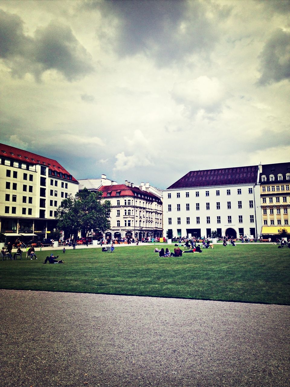 architecture, building exterior, built structure, sky, grass, cloud - sky, city, cloudy, lawn, cloud, incidental people, building, tree, city life, large group of people, day, residential building, residential structure, outdoors