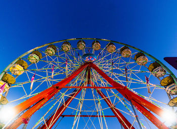 Low angle view of ferris wheel against clear blue sky