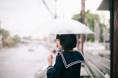 Woman holding umbrella standing in rainy season