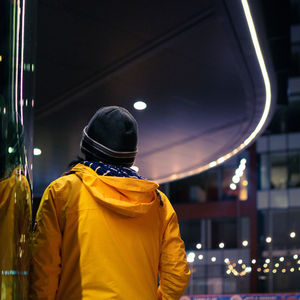 Rear view of man standing in illuminated city at night