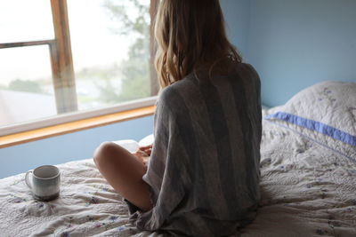 Rear view of woman relaxing on bed