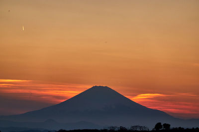Scenic view of silhouette mountain against orange sky