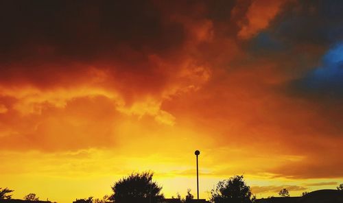 Low angle view of silhouette trees against dramatic sky