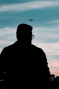 Rear view of silhouette man standing against sky