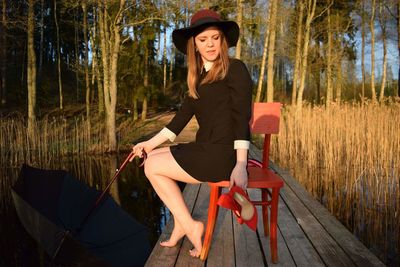 Young woman wearing hat sitting in forest