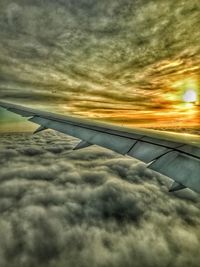 View of airplane wing over clouds during sunset