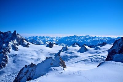 Scenic view of snow covered mountains against clear blue sky