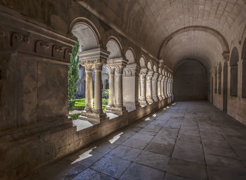 Long corridor with white antique columns illuminated by sunlight