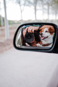 Portrait of woman photographing through car