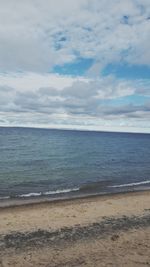 View of calm beach against cloudy sky