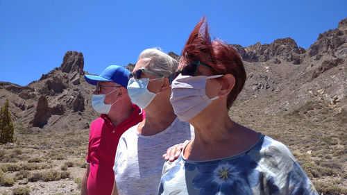 Midsection of friends against mountains against clear blue sky