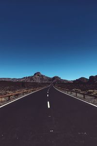 Road by mountain against clear blue sky